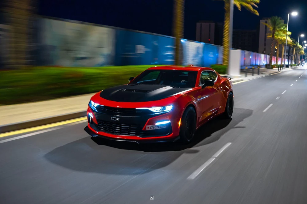 A red car captured in motion on a road at night.