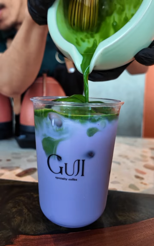 Green matcha poured into a purple iced drink at Guji.